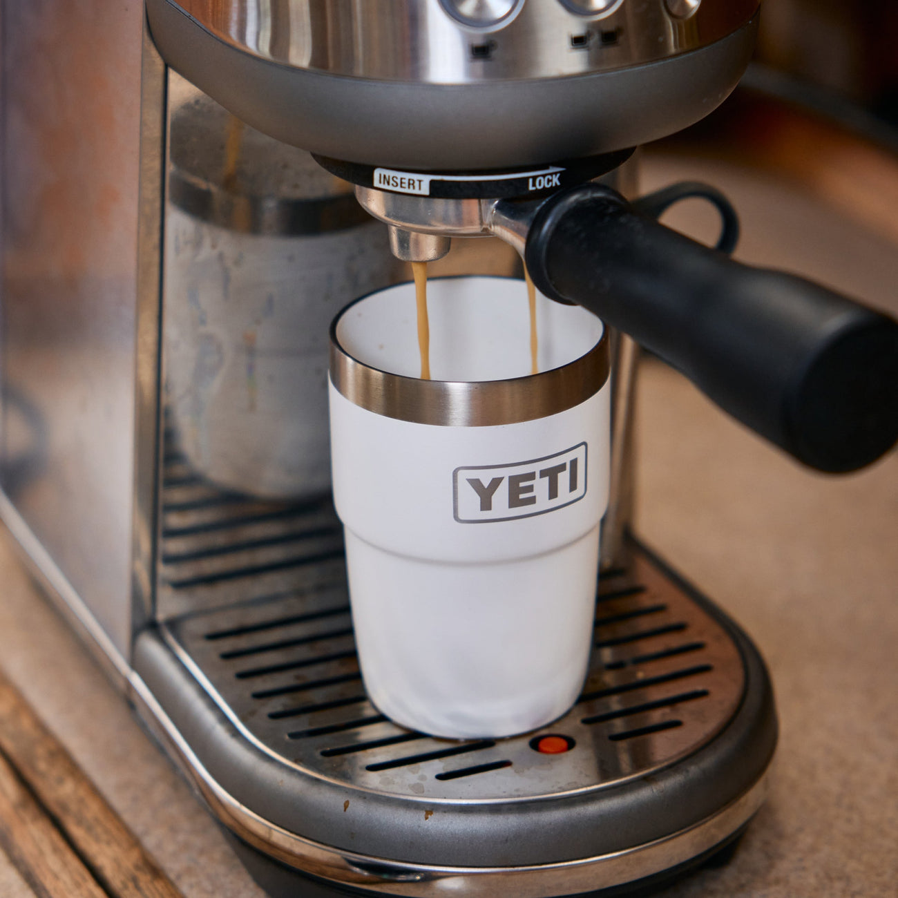 Espresso machine pouring coffee into a YETI-branded tumbler.