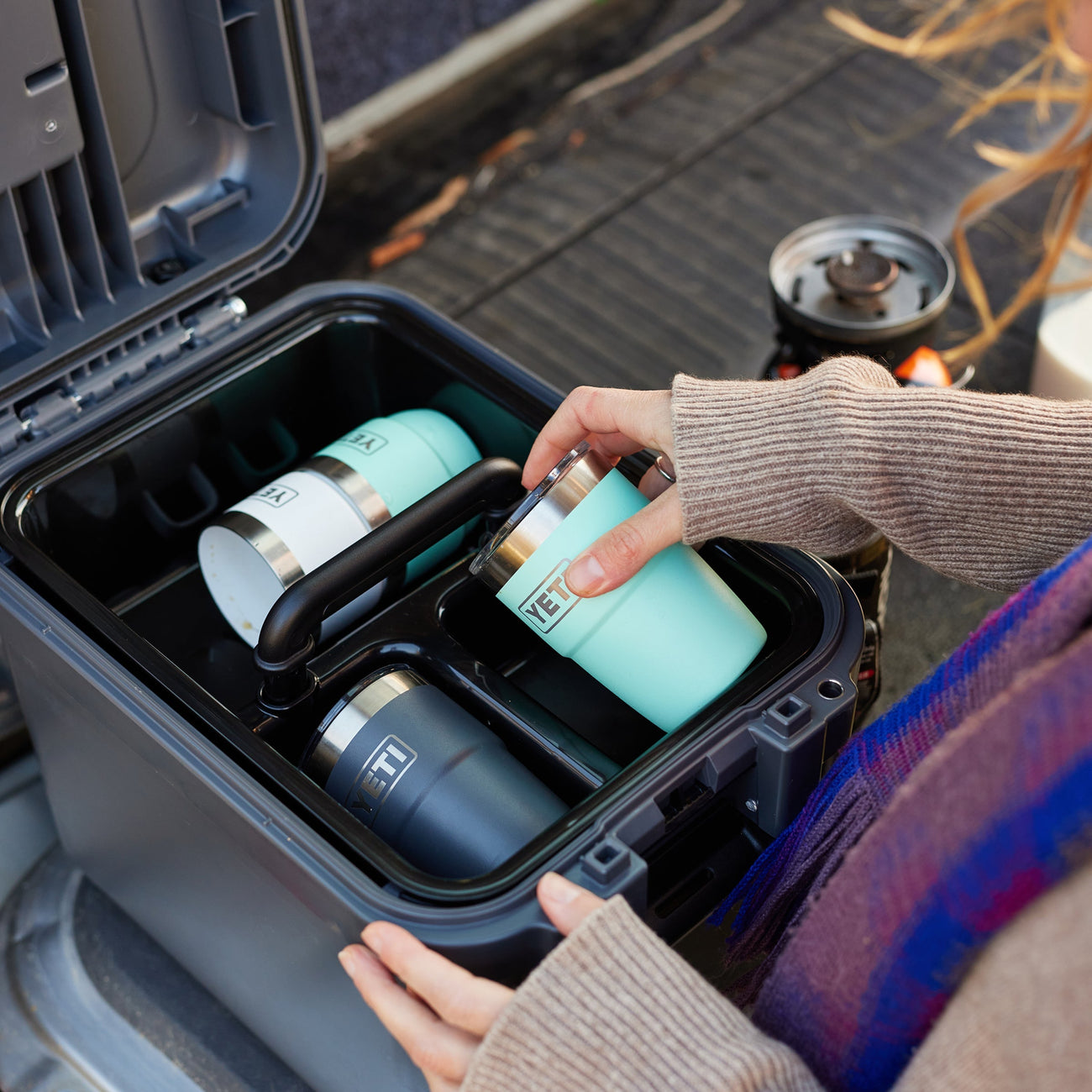 Person organizing insulated cups in a black storage case.