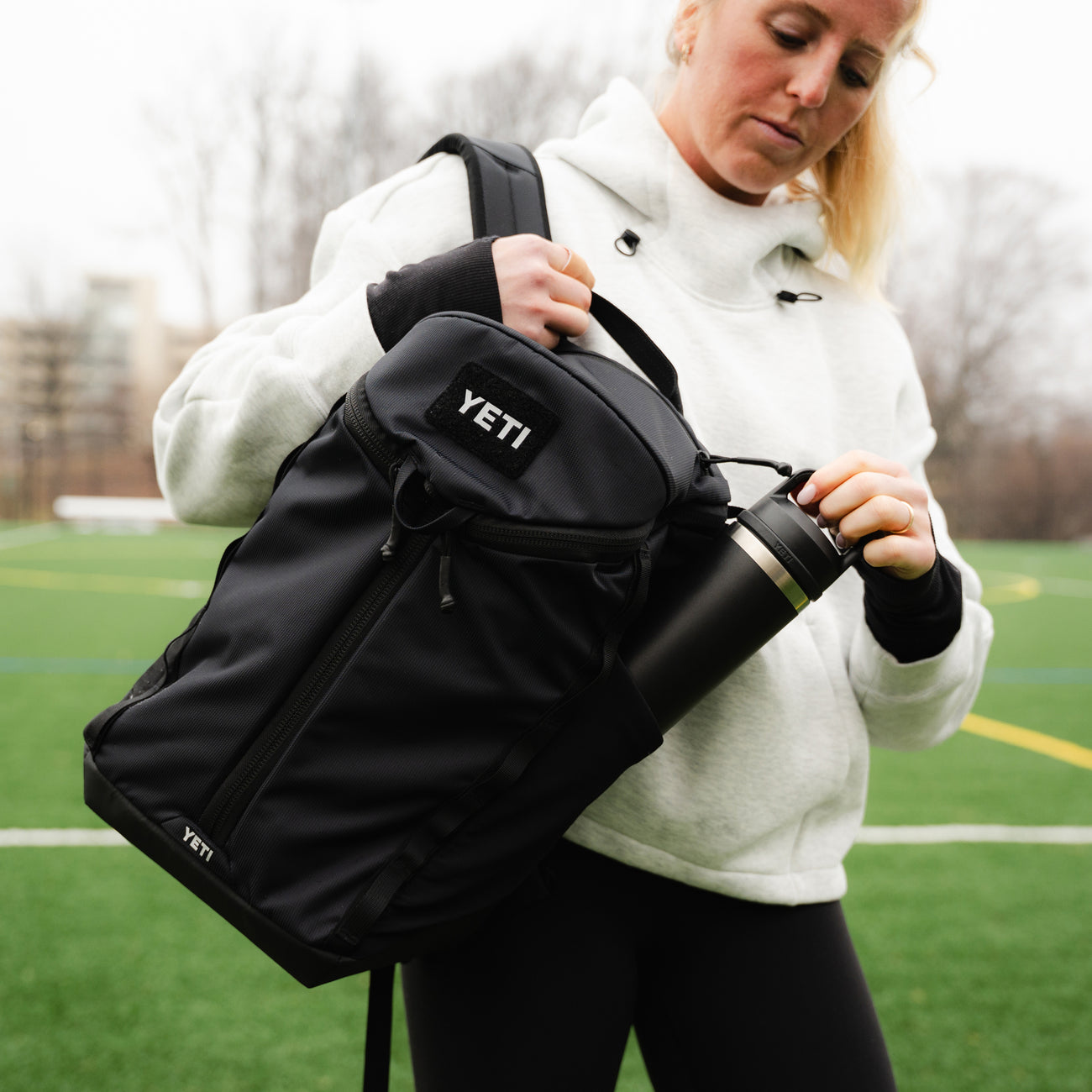 Person holding a black YETI bag on a sports field