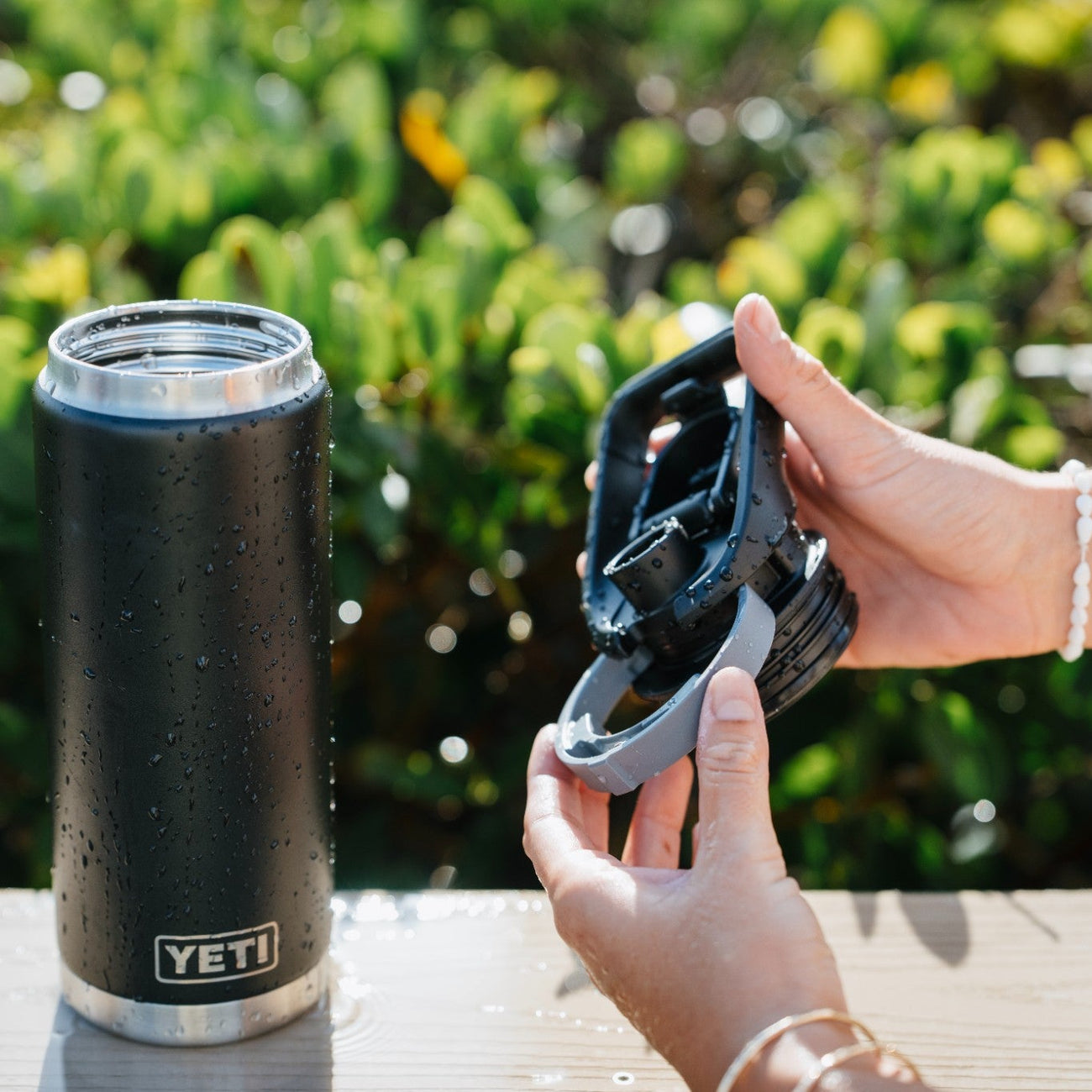Black YETI bottle on a wooden surface with greenery in the background